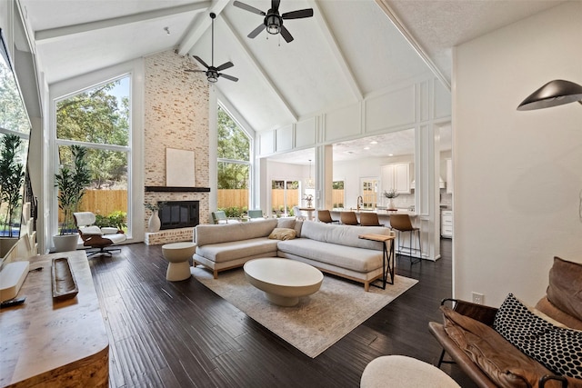 sunroom / solarium with ceiling fan, a fireplace, and lofted ceiling with beams