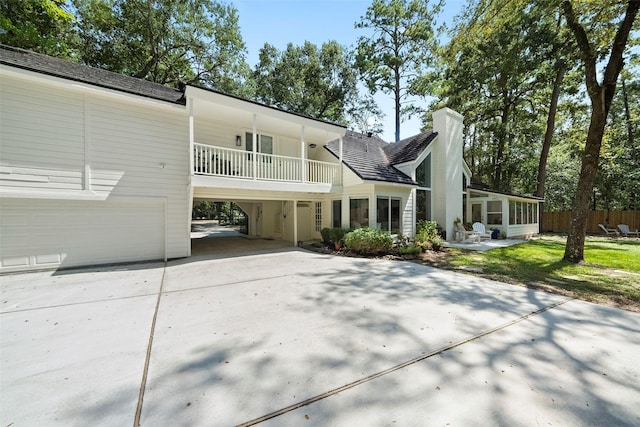 rear view of house featuring a sunroom, a garage, and a balcony