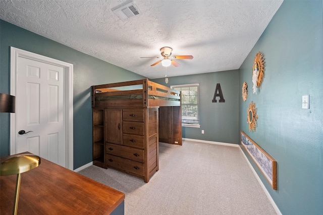 bedroom featuring light carpet, a textured ceiling, and ceiling fan