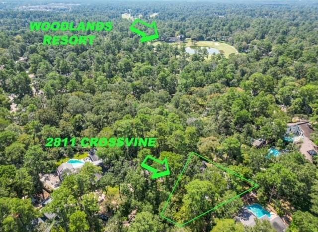 view of property location with a forest, property parcel outlined, and a nearby body of water