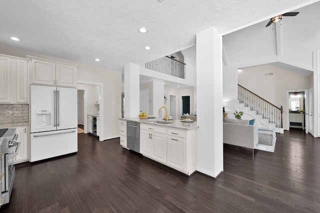 kitchen with premium appliances, a ceiling fan, light stone counters, a sink, and white cabinetry