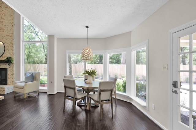 dining room featuring a textured ceiling, a fireplace, dark wood-type flooring, and baseboards