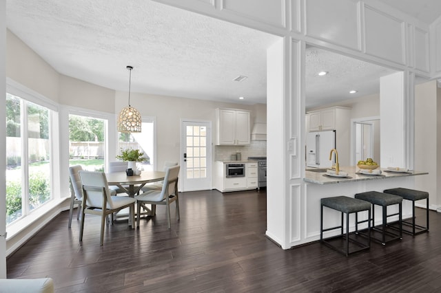 dining space with healthy amount of natural light, a textured ceiling, dark wood-style floors, and recessed lighting