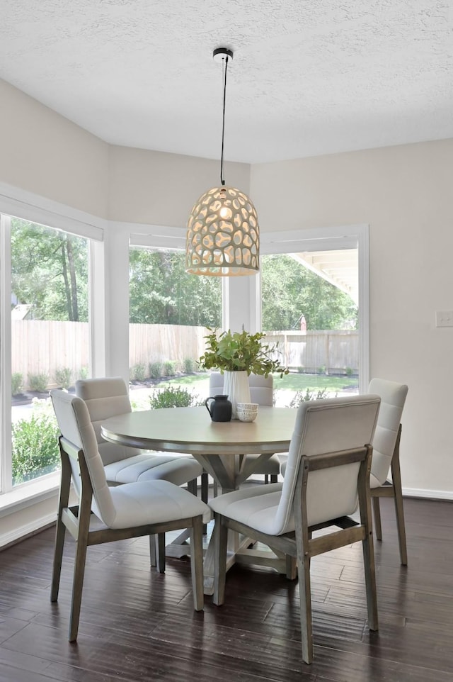 dining area with healthy amount of natural light, dark wood-type flooring, and a textured ceiling