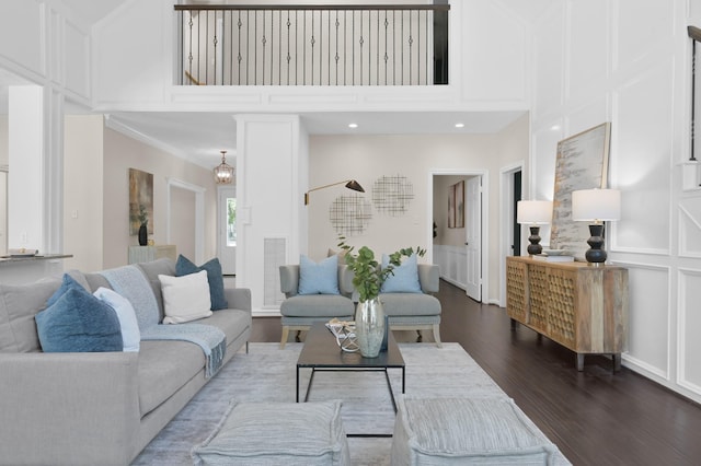 living area featuring a towering ceiling, dark wood-type flooring, and a decorative wall