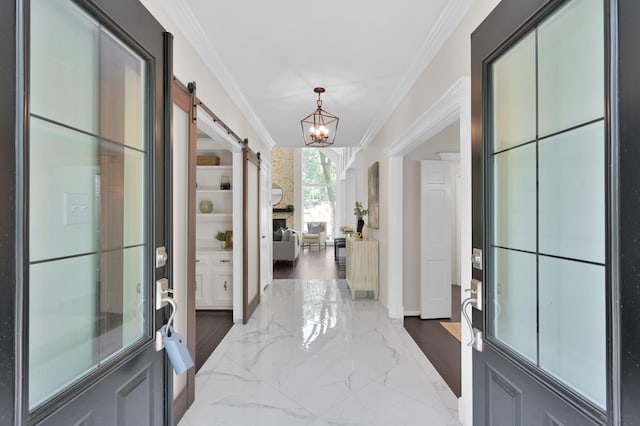entryway featuring crown molding, a barn door, a chandelier, marble tiled floors, and baseboards