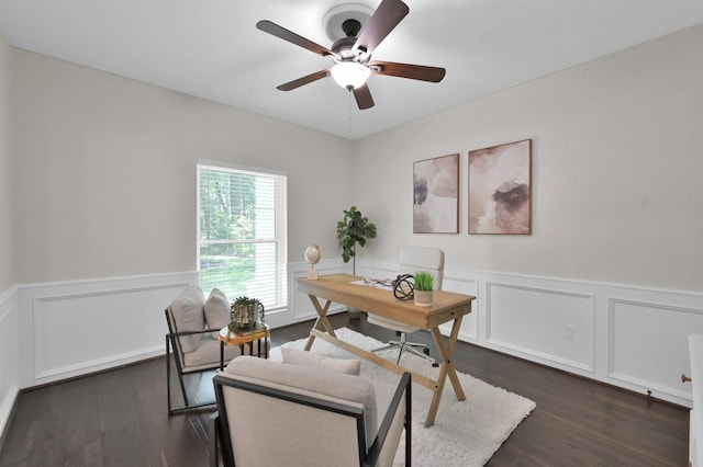 home office with a ceiling fan, wainscoting, dark wood-style floors, and a decorative wall