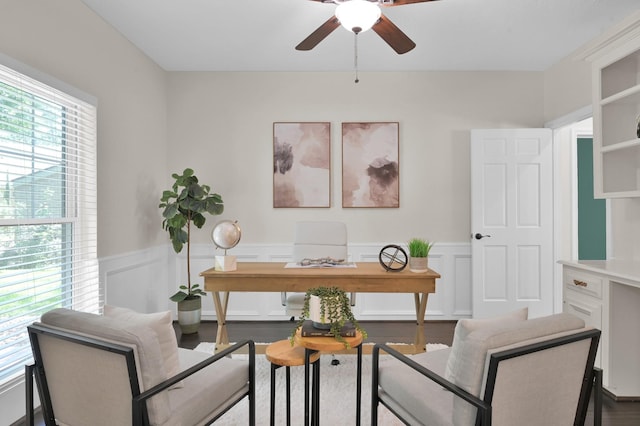 home office with ceiling fan, a wainscoted wall, a decorative wall, and wood finished floors