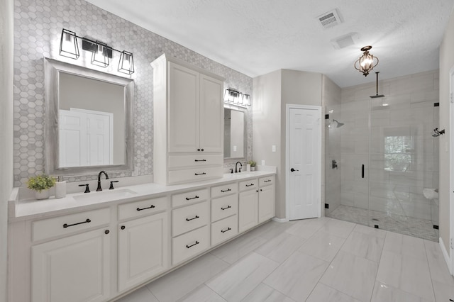 full bathroom with a shower stall, a textured ceiling, double vanity, and baseboards
