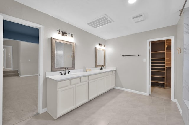 full bath featuring double vanity, a walk in closet, and baseboards
