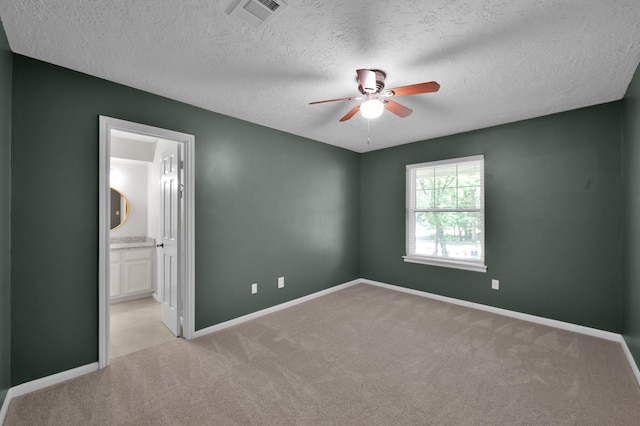unfurnished bedroom featuring a textured ceiling, carpet flooring, baseboards, connected bathroom, and ceiling fan