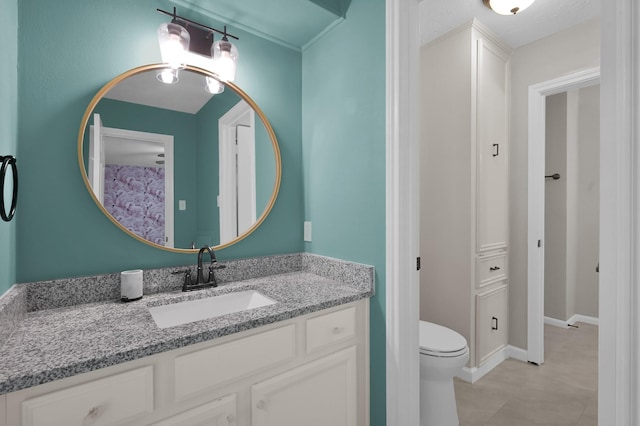 bathroom featuring toilet, vanity, and baseboards