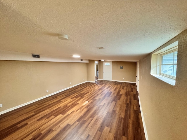 basement featuring a textured ceiling and dark wood-type flooring