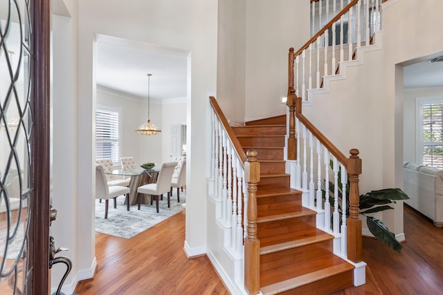 stairs featuring wood-type flooring and ornamental molding