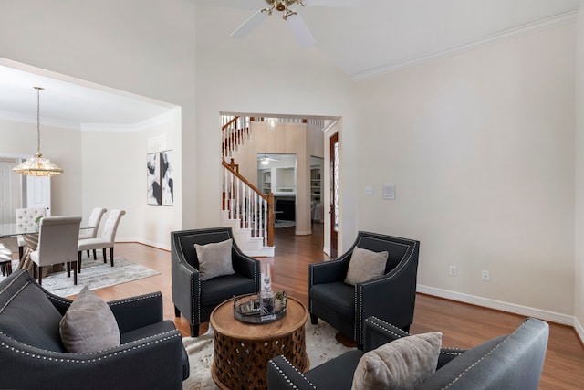 living room featuring hardwood / wood-style floors, ceiling fan with notable chandelier, high vaulted ceiling, and crown molding