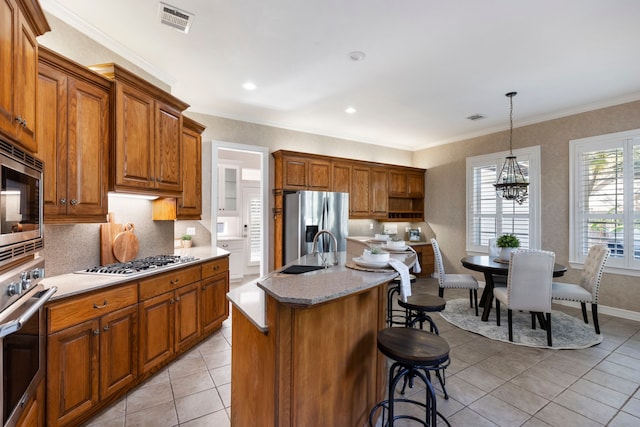 kitchen featuring pendant lighting, an inviting chandelier, a center island with sink, appliances with stainless steel finishes, and a kitchen bar