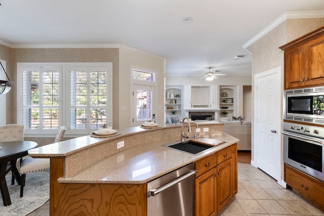 kitchen featuring stainless steel appliances, a kitchen island with sink, ornamental molding, and sink