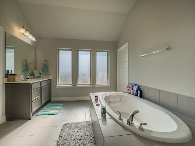 bathroom featuring tile patterned floors, vanity, a relaxing tiled tub, and lofted ceiling