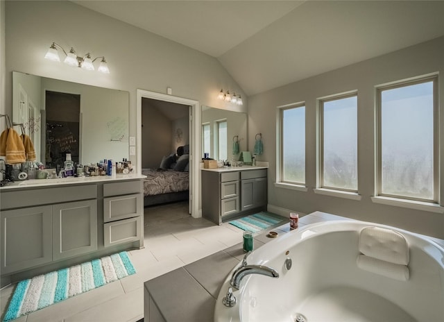 bathroom featuring a bathing tub, tile patterned flooring, vanity, and vaulted ceiling