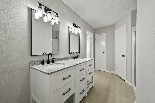 bathroom with tile patterned floors, vanity, and a textured ceiling