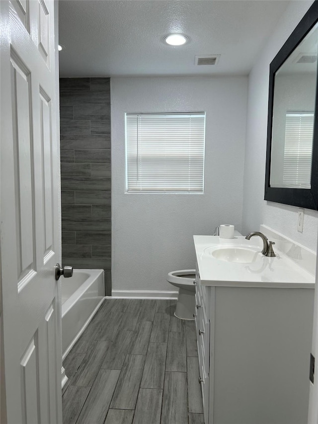 full bathroom featuring vanity, toilet, washtub / shower combination, and a textured ceiling