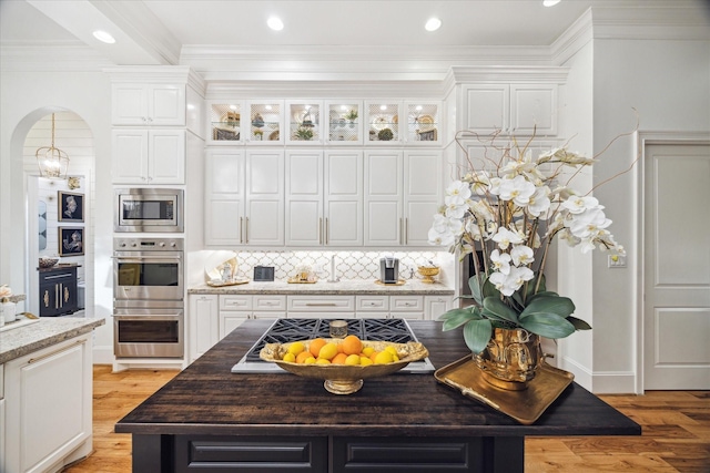 kitchen featuring decorative backsplash, light stone countertops, stainless steel appliances, white cabinets, and a kitchen island