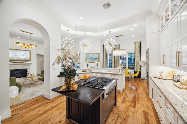 kitchen with pendant lighting, a center island, light stone counters, and white cabinets