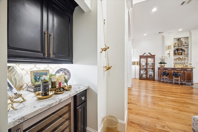 bar featuring built in shelves, light stone countertops, beverage cooler, and light hardwood / wood-style floors