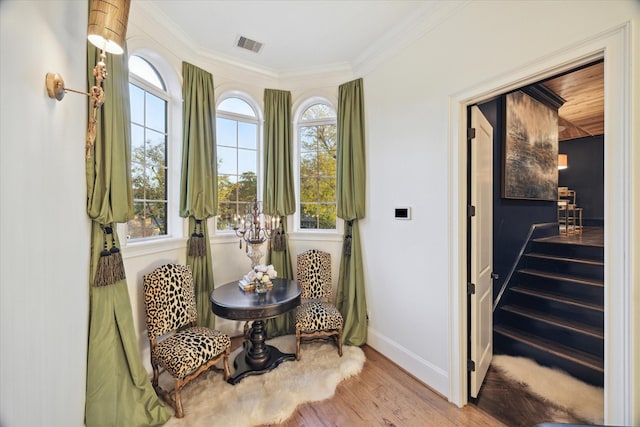 living area featuring plenty of natural light, light wood-type flooring, and ornamental molding