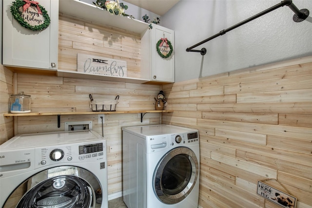 laundry room featuring washer and clothes dryer, cabinets, and wooden walls