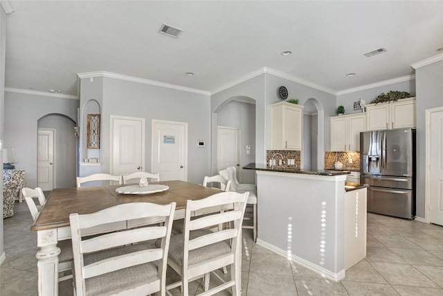 kitchen with decorative backsplash, stainless steel fridge with ice dispenser, crown molding, and light tile patterned flooring