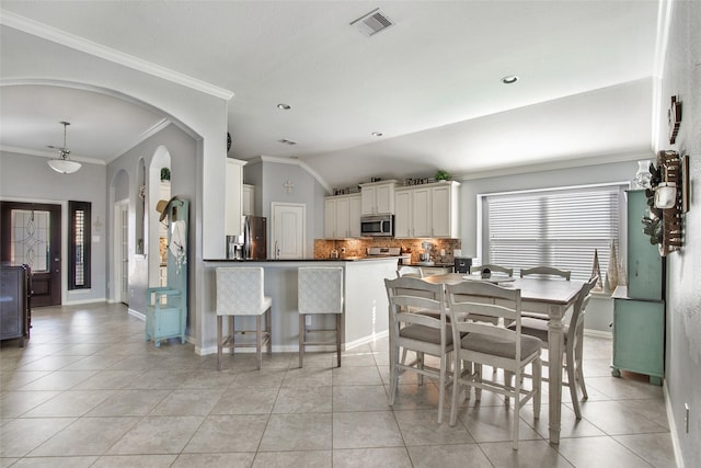 tiled dining space featuring vaulted ceiling and ornamental molding