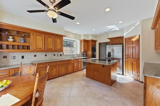 kitchen featuring light stone counters, backsplash, a breakfast bar area, a kitchen island, and black appliances