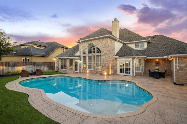 pool at dusk featuring french doors and a patio area