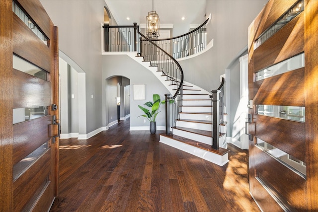 foyer entrance featuring a towering ceiling, a notable chandelier, and dark hardwood / wood-style flooring