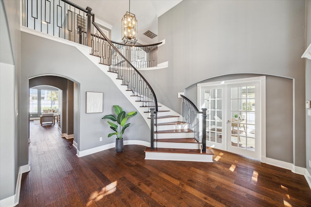 entryway featuring a notable chandelier, a towering ceiling, and dark hardwood / wood-style floors