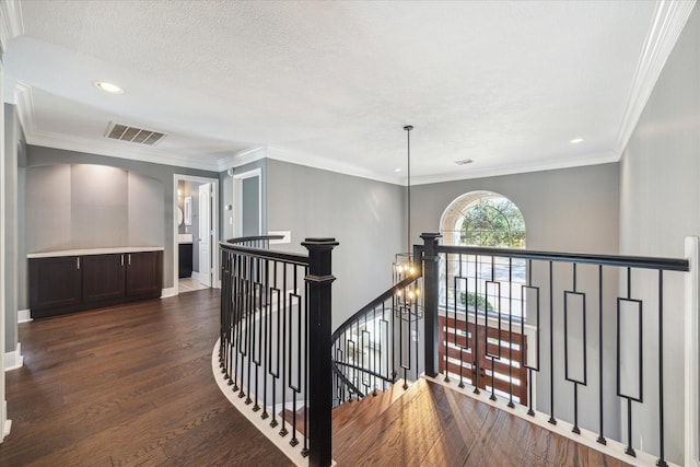 hall featuring dark hardwood / wood-style flooring, ornamental molding, and a textured ceiling