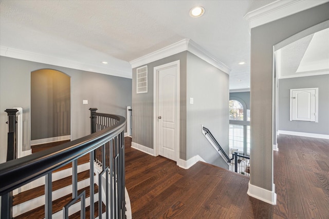 corridor featuring crown molding, dark wood-type flooring, and a textured ceiling