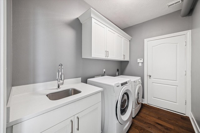 laundry area with sink, washing machine and dryer, dark hardwood / wood-style floors, cabinets, and a textured ceiling