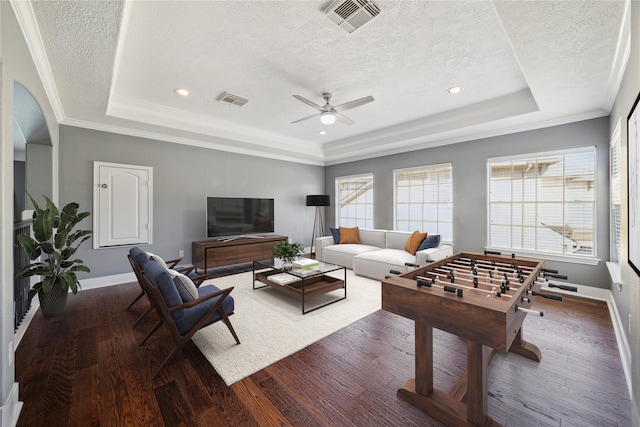 rec room with dark wood-type flooring, ornamental molding, and a raised ceiling