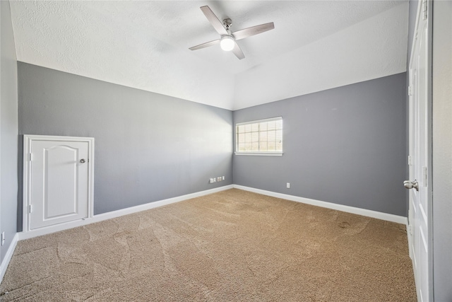 carpeted empty room with ceiling fan, lofted ceiling, and a textured ceiling