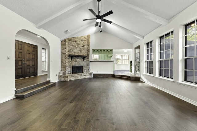 unfurnished living room with a healthy amount of sunlight, ceiling fan, dark wood-type flooring, and a textured ceiling