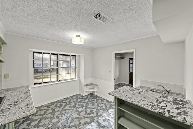 kitchen featuring light stone countertops, sink, crown molding, a textured ceiling, and green cabinetry