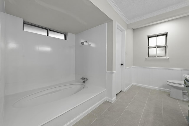 bathroom featuring a tub to relax in, tile patterned flooring, a textured ceiling, and toilet