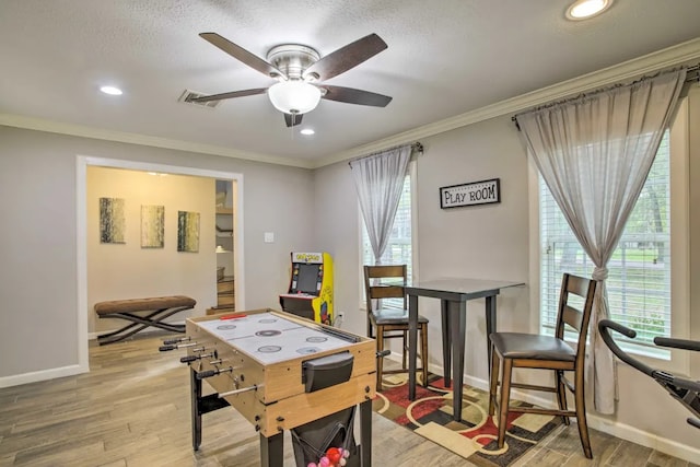 rec room with ceiling fan, crown molding, and light hardwood / wood-style flooring