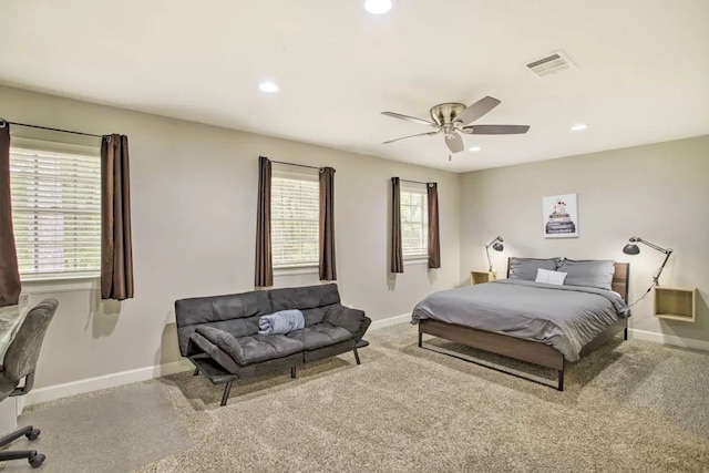 bedroom with multiple windows, ceiling fan, and light carpet