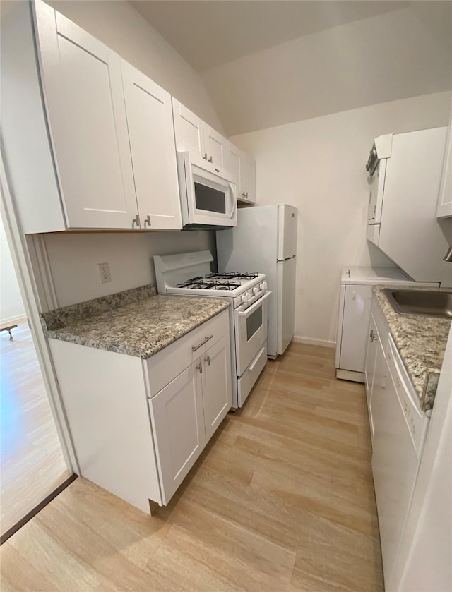 kitchen with white cabinets, light hardwood / wood-style floors, white appliances, and sink