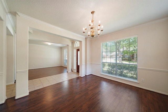 spare room with hardwood / wood-style flooring, ornamental molding, and an inviting chandelier