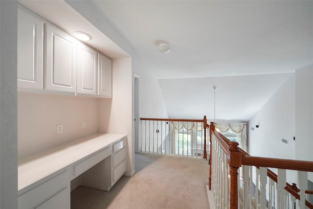 hallway featuring light carpet and vaulted ceiling