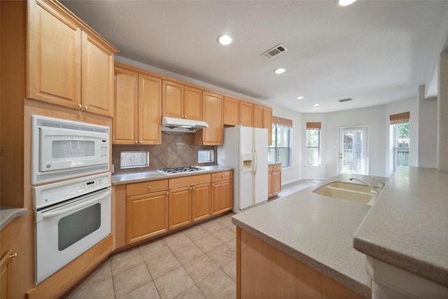 kitchen featuring tasteful backsplash, white appliances, sink, light brown cabinets, and light tile patterned floors